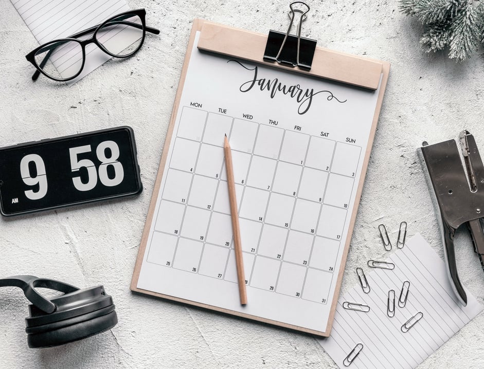 Clipboard with calendar placed on desk amidst stationery